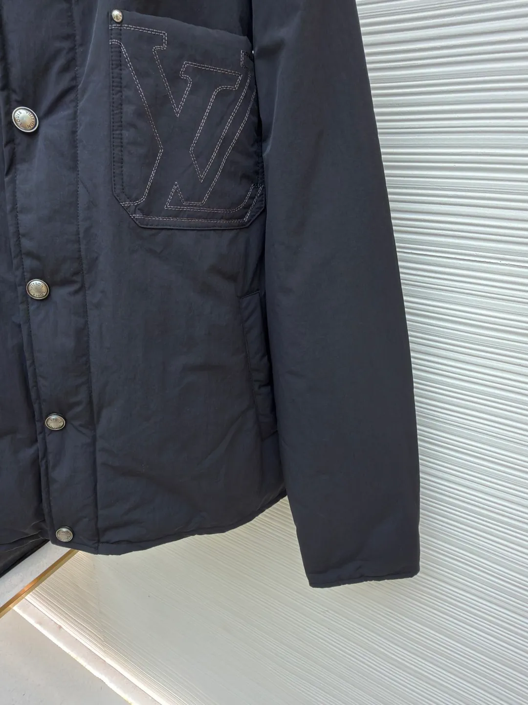 LOUIS VUITTON Corduroy collar waterproof work jacket ●Original version: purchased and developed in 19699 ●Item number: 1681946-C30 ●Fabric: nylon fabric ●Technology: embroidery production ●Color: black ●Version: fitted version ●Weight: about 550 grams ●Size: 44-46-48-50 ●Description: Made of water-repellent nylon blended fabric, the body is made of precision woven craftsmanship to create a matte texture, taking into account both lightness and stiffness. The collar is made of ribbed corduroy-effect leather, which uses trompe l'oeil techniques to simulate the texture of corduroy. It feels soft and has a retro look. The chest patch pocket adopts double-line topstitch quilting technology, embedded with three-dimensional LV letter embroidery, and reinforced with metal rivets on the edge, which is both decorative and durable. The front is equipped with pearlescent mother-of-pearl buttons, and the metal base is polished and nickel-plated, with a delicate luster and not easily oxidized. The inner lining is Damier jacquard fabric, and the quilting process is filled with light and warm fibers. The cuffs and hem are narrowed with the same fabric. The overall stitching error is controlled within 0.1cm, and the Italian workshop hand-finishes the details. The overall wiring is straight and delicate, the fabric is comfortable and soft, and the color is consistent without color difference. It can be matched with the same style to create a fashionable look and control various occasions. Customized accessories, complete with three standards, same style for men and women!